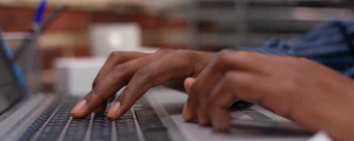 gros-plan-mains-afro-americaines-tapant-donnees-commerciales-clavier-ordinateur-portable-dans-bureau-mur-briques-demarrage-concentrez-vous-employe-demarrage-utilisant-ord